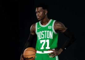 Dennis Schröder posiert im Trikot der Boston Celtics mit einem Basketball