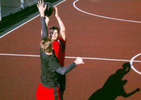 Zwei Leute spielen Basketball, einer wird vom anderen im Wurf geblockt