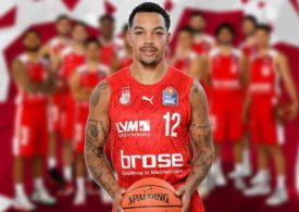 Justin Robinson von brose Bamberg vor einem geblurrten Teamfoto